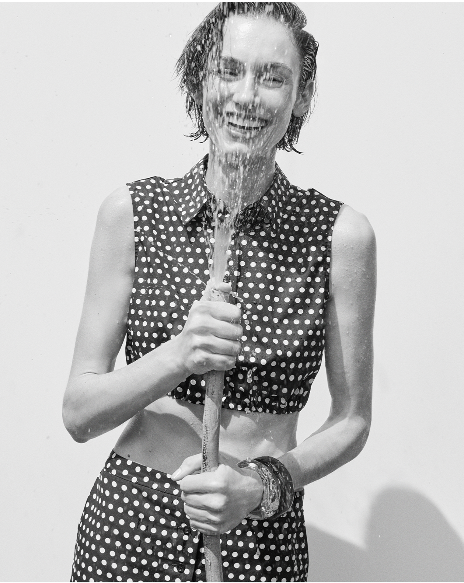 Model in a polka dot collared tank with a garden hose