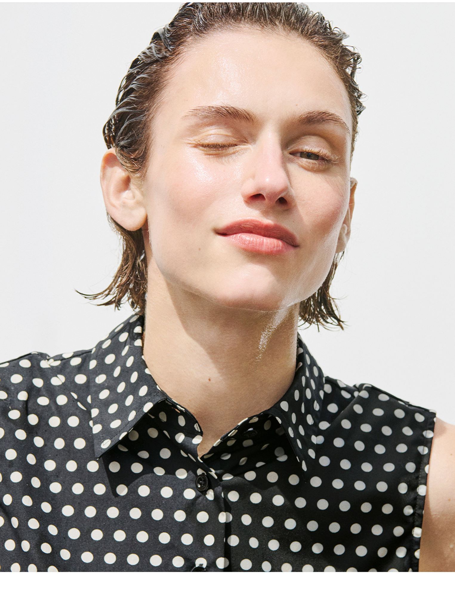 Model in a black and white polka dot tank winking