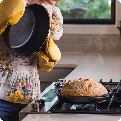 A baker in her kitchen with a freshly baked loaf of bread