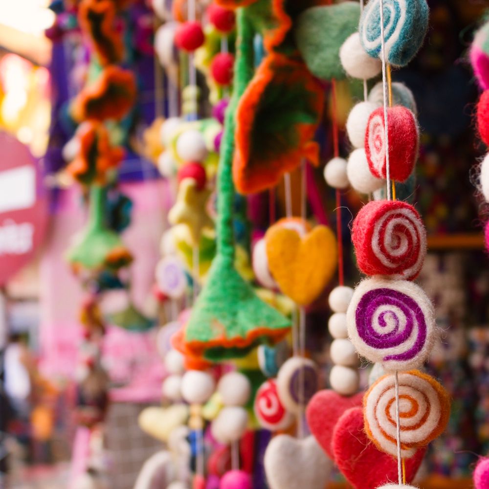 An array of whimsical, colorful felted objects hangs on display.