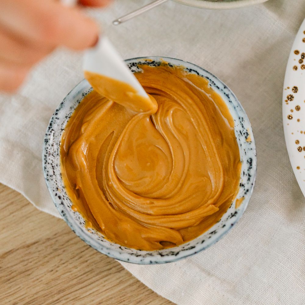 A speckled gray bowl filled with creamy peanut butter. 